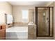 Relax in this primary bathroom featuring a tub with shower and a glass shower enclosure at 36179 W Cartegna Ln, Maricopa, AZ 85138