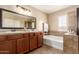 A primary bathroom featuring dual sinks, a soaking tub, and beautiful tile details at 36179 W Cartegna Ln, Maricopa, AZ 85138