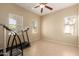 Bright bedroom showcasing a ceiling fan and tiled flooring, complemented by three windows providing ample natural light at 36179 W Cartegna Ln, Maricopa, AZ 85138