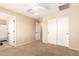 Neutral bedroom featuring a ceiling fan, carpeted floor, closet, and a bathroom entrance at 36179 W Cartegna Ln, Maricopa, AZ 85138