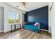 Well-lit bedroom with wood-style flooring, a view to the outside and a modern blue accent wall at 3817 E Patrick Ln, Phoenix, AZ 85050