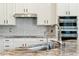 A kitchen with white cabinetry, subway tile backsplash, stainless steel appliances, granite countertops, and a large sink at 3817 E Patrick Ln, Phoenix, AZ 85050