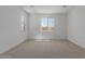 Bright bedroom featuring neutral carpet, large window, and white walls at 40595 W Michaels Dr, Maricopa, AZ 85138