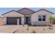 Inviting single-story home with a green front door, desert landscaping, and a two-car garage at 40595 W Michaels Dr, Maricopa, AZ 85138