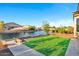 Picturesque backyard features artificial turf lawn, mature trees and waterfront view with patio area at 41584 W Springtime Rd, Maricopa, AZ 85138