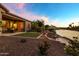 Stunning backyard featuring a cozy patio area, vibrant greenery, and a tranquil waterfront at 41584 W Springtime Rd, Maricopa, AZ 85138