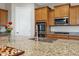 Close up of a kitchen island with granite countertops and a stainless steel sink with a white door and stainless appliances nearby at 41584 W Springtime Rd, Maricopa, AZ 85138