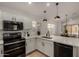 Bright kitchen featuring white cabinets, stainless steel appliances, and modern pendant lighting at 42067 W Anne Ln, Maricopa, AZ 85138