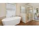 Bright bathroom with a soaking tub under a glass block window and a seamless glass shower with neutral tile and dark wood floors at 4960 E Dale Ln, Cave Creek, AZ 85331