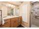 Bathroom featuring double sinks, wooden cabinets, and tiled shower with glass doors at 5209 N 78Th St, Scottsdale, AZ 85250