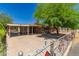 A single-story brick house with a carport and spacious driveway, surrounded by lush trees and a chain-link fence at 6100 N 36Th Ave, Phoenix, AZ 85019