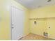 Bright laundry room features white door, yellow walls, tan tile, and has hook ups for washer and dryer at 6944 S Morning Dew Ln, Buckeye, AZ 85326