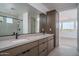 Modern bathroom featuring an extended vanity with double sinks and sleek fixtures, alongside a mirror and storage cabinet at 7956 W Griswold Rd, Peoria, AZ 85345