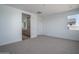 Bright bedroom with neutral carpet, white walls and trim, a window, and an ensuite bathroom with a long vanity at 7956 W Griswold Rd, Peoria, AZ 85345