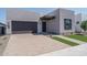 Contemporary home exterior showcases a dark garage, brick driveway, and xeriscaped yard at 7956 W Griswold Rd, Peoria, AZ 85345