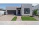 Modern home exterior with a dark garage door, brick driveway and minimalist landscaping at 7956 W Griswold Rd, Peoria, AZ 85345