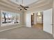Bright bedroom with plush carpets, a ceiling fan, plantation shutters, and a view into the entry hall at 8031 W Morten Ave, Glendale, AZ 85303
