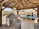 Outdoor kitchen with built-in grill and bar, perfect for entertaining in style at 8031 W Morten Ave, Glendale, AZ 85303