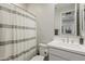Bright bathroom with a modern vanity, decorative mirror, and neutral-striped shower curtain at 9352 E Saturn Ave, Mesa, AZ 85212