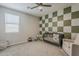 Bright bedroom featuring a checkerboard accent wall, a crib, and a comfortable chair at 9352 E Saturn Ave, Mesa, AZ 85212