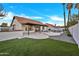 Spacious backyard with a tiled roof, a rock waterfall pool, an artificial lawn, and palm trees at 1001 N Nielson St, Gilbert, AZ 85234