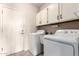 Laundry room with modern washer and dryer, utility sink, and storage cabinets at 11206 W Sieno Pl, Avondale, AZ 85392