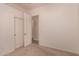 A bedroom with beige walls and carpeted floor leads into another room at 11312 E Enrose St, Mesa, AZ 85207