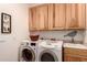A laundry room with wood cabinets, sink, and a front loading washer and dryer at 11312 E Enrose St, Mesa, AZ 85207