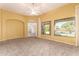 Living room with neutral carpet, a ceiling fan, and windows looking to the backyard and pool at 11312 E Enrose St, Mesa, AZ 85207