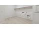Spacious laundry room featuring tile floors, utility sink hookups, and convenient upper shelving at 15389 W Cottontail Ln, Surprise, AZ 85387