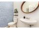 This bathroom features unique blue and white wallpaper, modern fixtures, and a stylish round mirror at 15862 W Fillmore St, Goodyear, AZ 85338
