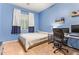Bright bedroom with blue walls, a comfortable bed, a practical desk setup, and ample natural light at 15862 W Fillmore St, Goodyear, AZ 85338