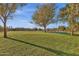Scenic park view with mature trees, green grass, a swing set, and nearby houses at 1633 E Lakeside Dr # 127, Gilbert, AZ 85234