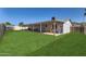 Expansive backyard featuring a covered patio, grassy lawn, and partial view of the neighborhood at 1718 W Voltaire Ave, Phoenix, AZ 85029