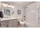 Bright bathroom with a white vanity, decorative round mirror, and combined tub and shower at 1718 W Voltaire Ave, Phoenix, AZ 85029