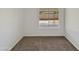 A carpeted bedroom with neutral walls showcasing a bright view to the yard outside at 1739 E Carter Rd, Phoenix, AZ 85042