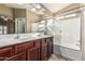 Bathroom featuring dual sinks, dark cabinets, and a large glass shower at 19576 N Portarosa Ct, Maricopa, AZ 85138