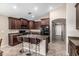Modern kitchen featuring stainless steel appliances, an island with seating, and sleek dark wood cabinets at 19576 N Portarosa Ct, Maricopa, AZ 85138