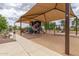 Covered playground with various play structures and seating areas, providing a safe and fun environment at 19576 N Portarosa Ct, Maricopa, AZ 85138