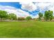Expansive green park with a playground area surrounded by lush trees and open space at 19576 N Portarosa Ct, Maricopa, AZ 85138