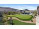 A private backyard oasis featuring a putting green, an outdoor kitchen, and lush landscaping at 20795 W San Juan Ave, Buckeye, AZ 85396
