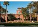 Verrado Golf Club entrance with manicured landscaping, framed by palm trees and lush greenery under a clear sky at 20795 W San Juan Ave, Buckeye, AZ 85396