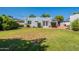 Backyard with green lawn, white stucco walls, patio and manicured shrubs at 317 E Orange Dr, Phoenix, AZ 85012