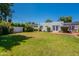 Wide backyard view showcasing the lawn, landscaping, white stucco facade, and patio at 317 E Orange Dr, Phoenix, AZ 85012