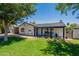 Charming single-story home featuring lush green lawn, mature trees, and a cozy covered front porch at 317 E Orange Dr, Phoenix, AZ 85012