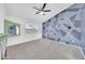 Bright bedroom featuring a geometric accent wall, ceiling fan, and natural light from the window at 3201 W Mohawk Ln, Phoenix, AZ 85027