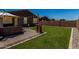 Spacious backyard features a well-maintained lawn, patio with seating, string lights, and a view of neighboring houses at 40380 W Jenna Ln, Maricopa, AZ 85138