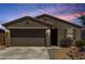 Charming single-story home featuring a two-car garage, desert landscaping, and a tiled roof against a vibrant sky at 40380 W Jenna Ln, Maricopa, AZ 85138