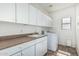 Functional laundry room featuring ample storage with white cabinets, a utility sink, and a modern washing machine at 4507 E Lantern Pl, Gilbert, AZ 85297
