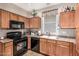 Traditional kitchen featuring wooden cabinets, black appliances, and a window over the sink at 5 N 87Th Ln, Tolleson, AZ 85353